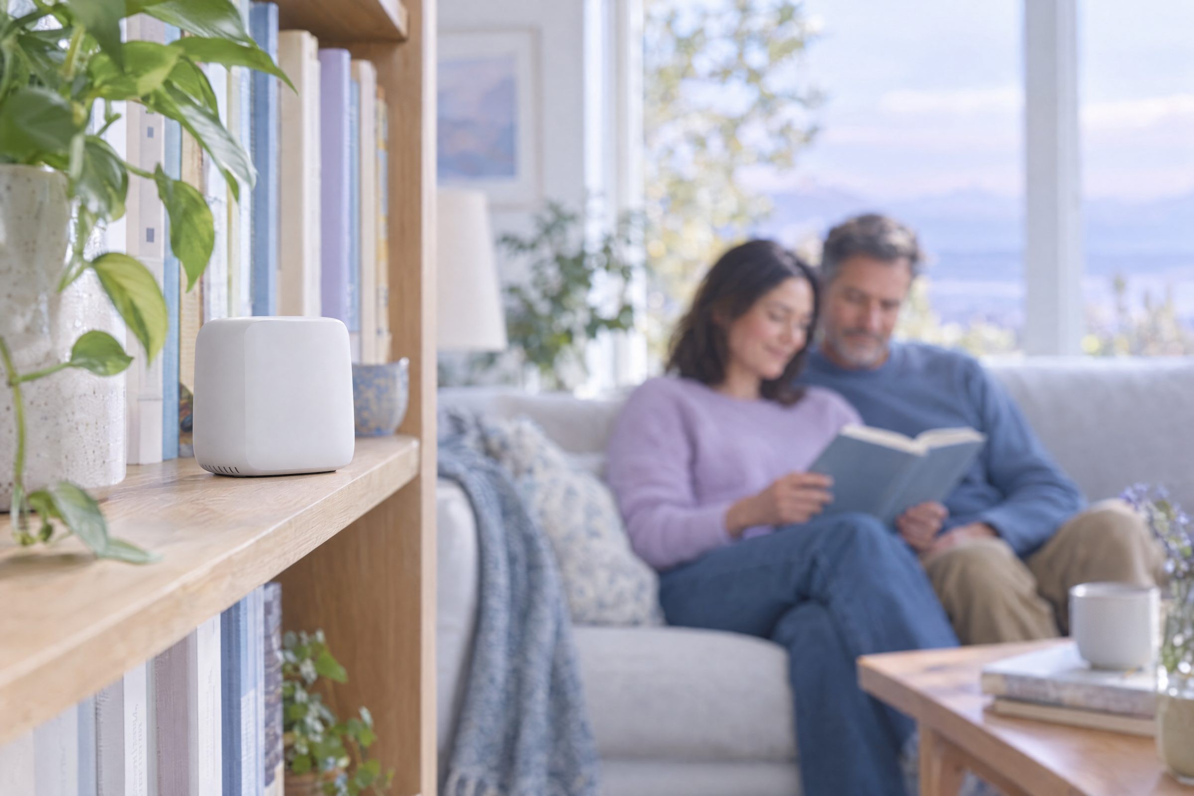 Small air monitor on a bookshelf with two people reading on a sofa behind