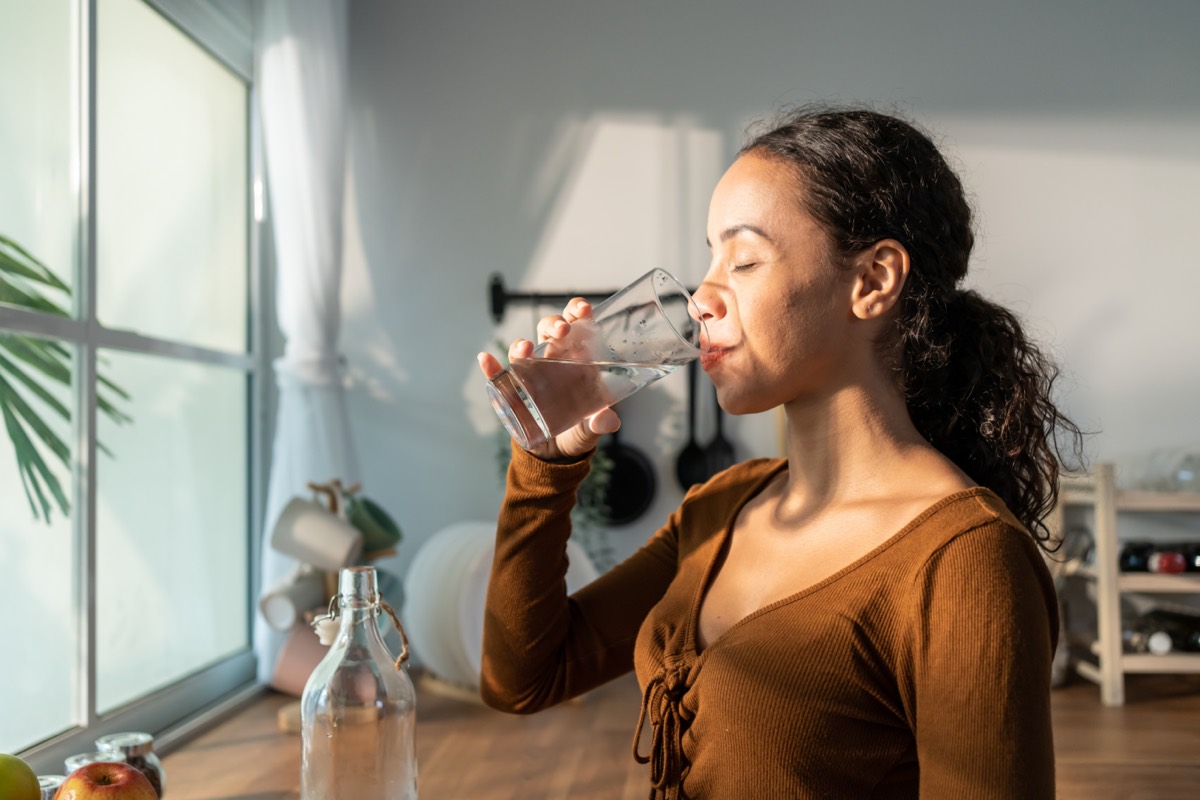 Lumen Metabolism Tracker (representative image): a woman with a glass of water in a bright kitchen